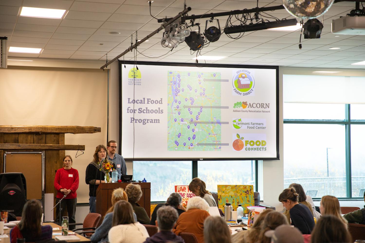 Netowrk members address the group, a projected slide behind them, showing illustrating local purchasing throughout the state