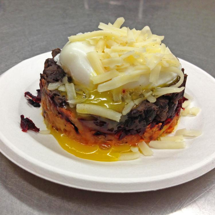 Plate with a serving of stacked potatoes topped with shredded cheese and sour cream.